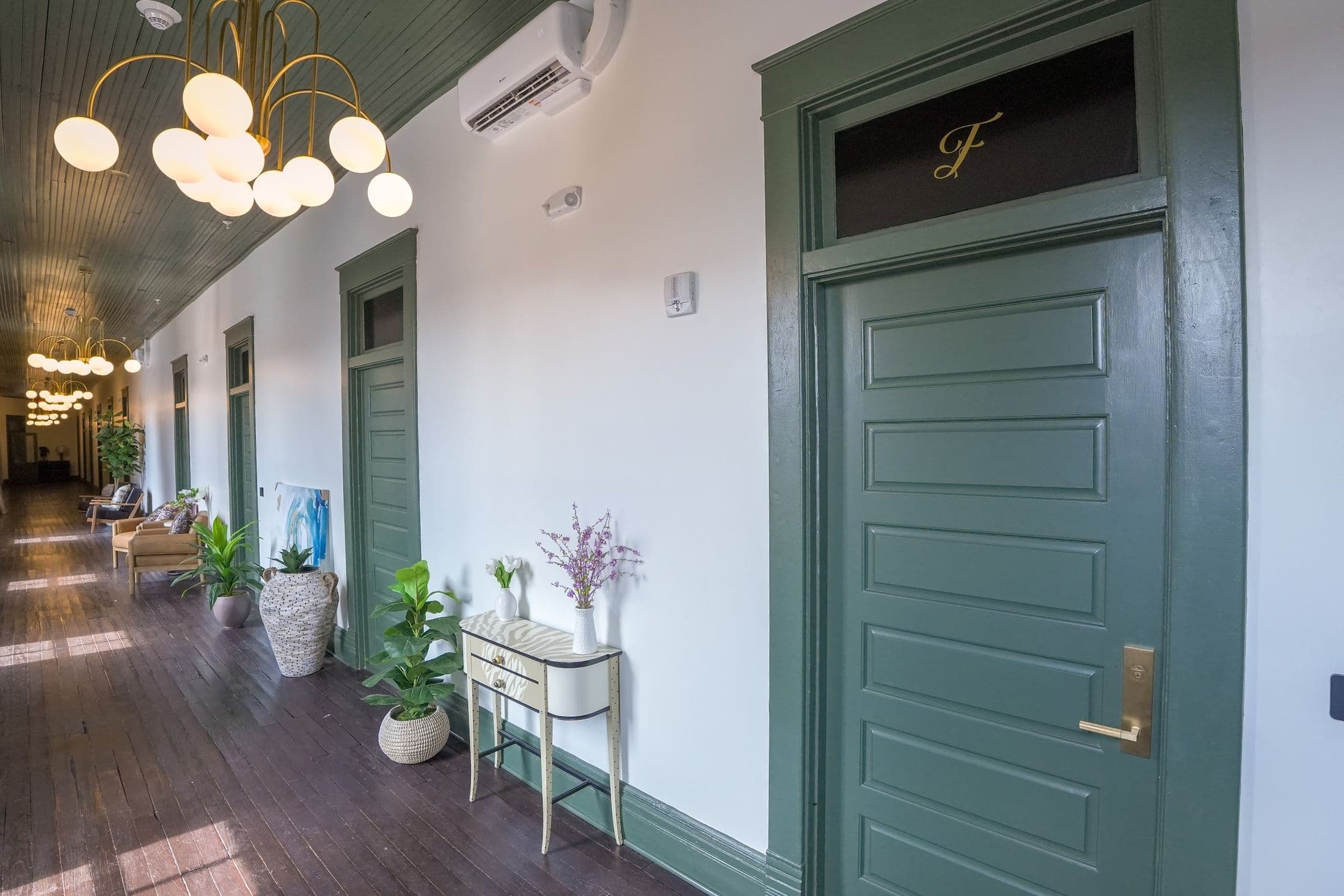 A green loft door at The Whistlestop with a gold letter and brass hardware